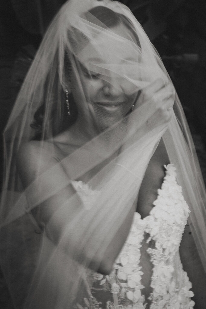Black and white documentary wedding photography of a bride smiling behind her veil in Lisbon.